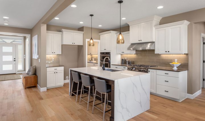 Bright and airy kitchen featuring modern white cabinetry, marble countertops, and stylish pendant lighting over an expansive island.