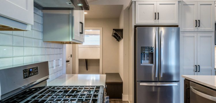 A contemporary kitchen setup with white cabinetry, a stainless steel range, and a subway tile backsplash, offering a clean and polished look, perfect for culinary enthusiasts.