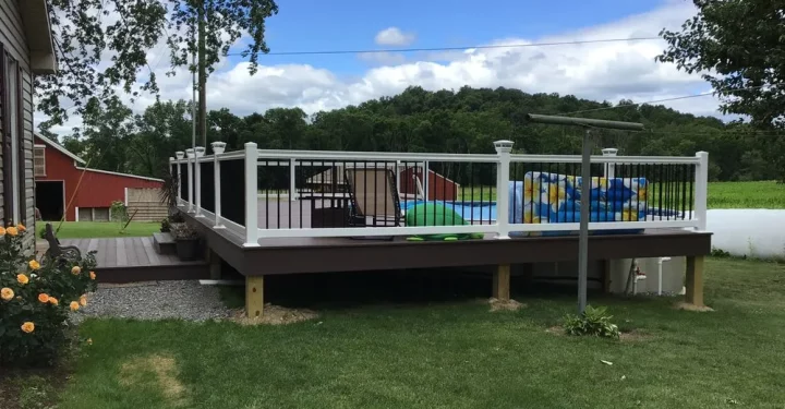 A generously sized deck featuring a refreshing pool and ample seating areas, surrounded by lush landscaping and open fields, perfect for summer relaxation and family fun.
