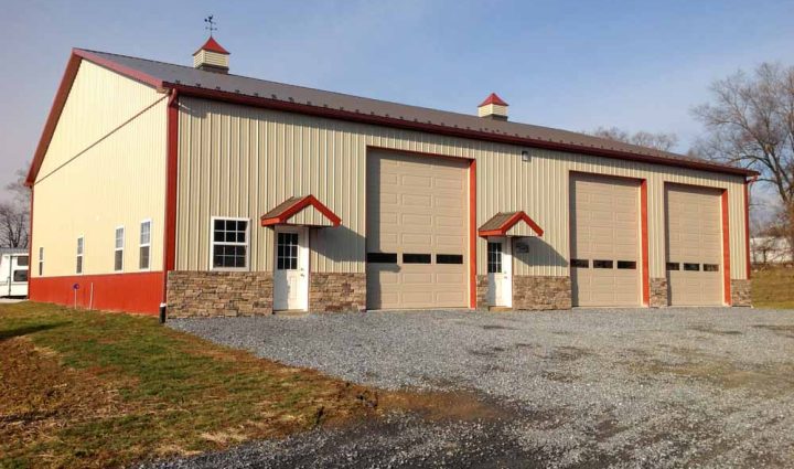 Large modern industrial garage with multiple bays, featuring a combination of red and beige colors, stone accents, and practical design for utility and storage.