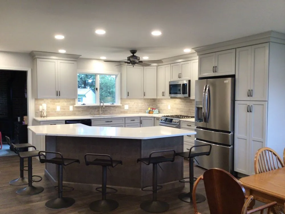 A sleek and modern kitchen outfitted with light gray cabinetry, a large center island with bar stools, and state-of-the-art appliances, making it ideal for both cooking and entertaining.